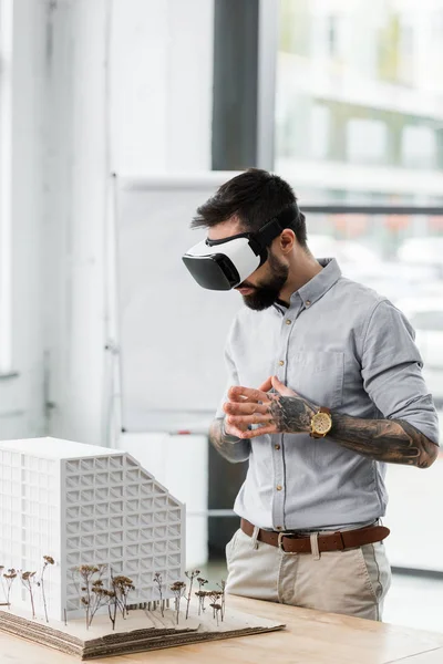 Virtual reality architect in virtual reality headset looking at model of house — Stock Photo