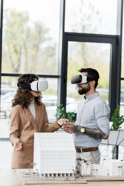 Arquitectos de realidad virtual en auriculares de realidad virtual hablando en la oficina - foto de stock