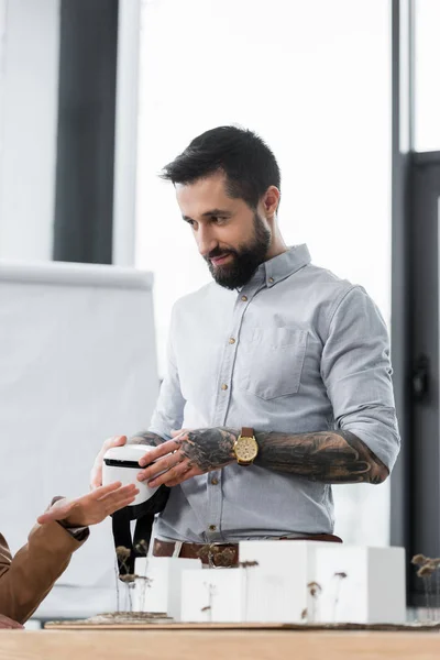 Virtual reality architect holding virtual reality headset talking with colleague — Stock Photo