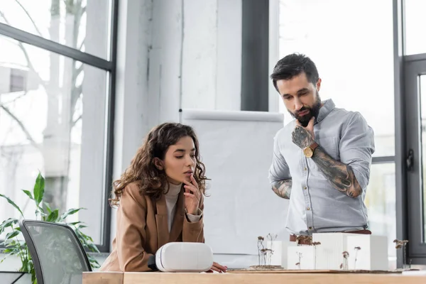 Pensive virtual reality architects looking at model of house — Stock Photo