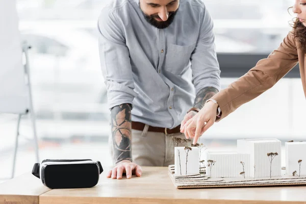 Cropped view of virtual reality architects pointing with finger at model of house — Stock Photo