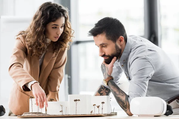 Arquitecto de realidad virtual señalando con el dedo y hablando con colega - foto de stock