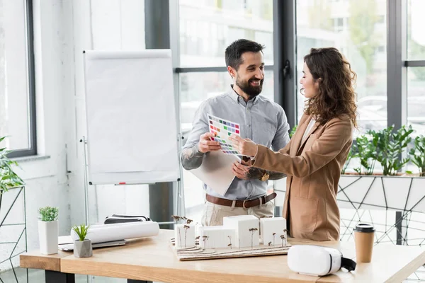 Smiling virtual reality architects talking and holding layout of colors — Stock Photo