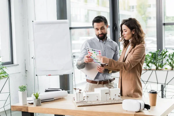 Smiling virtual reality architects looking at layout of colors — Stock Photo