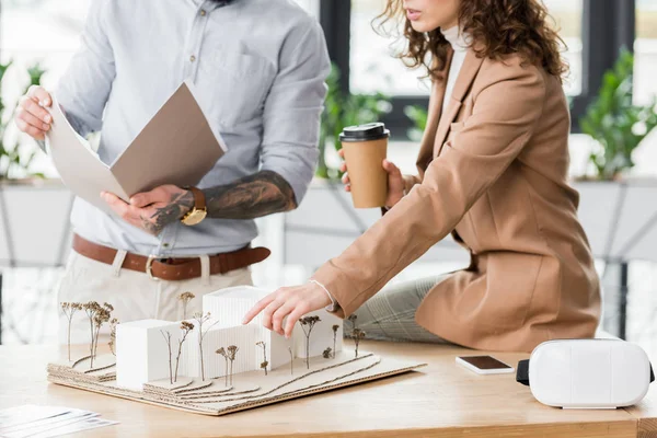 Cropped view of virtual reality architects pointing with finger and looking at model of house — Stock Photo