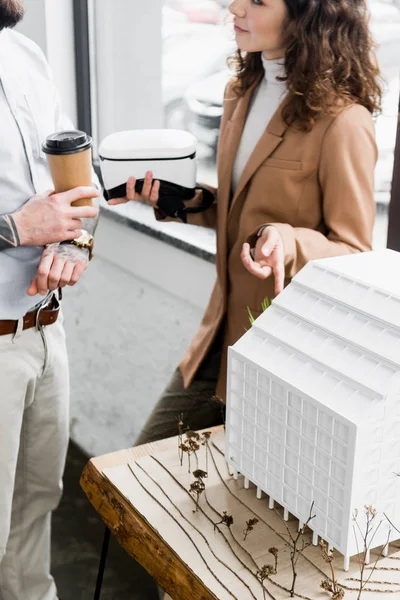 Cropped view of virtual reality architect holding virtual reality headset and talking with colleague — Stock Photo