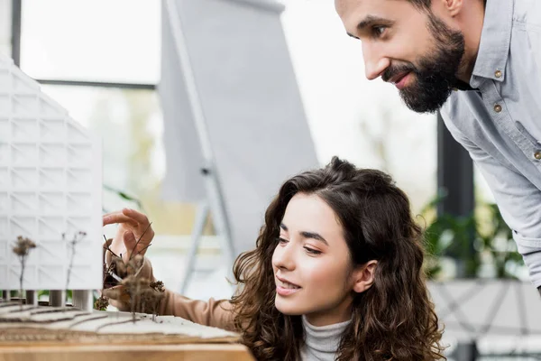 Smiling virtual reality architect looking at model of house — Stock Photo