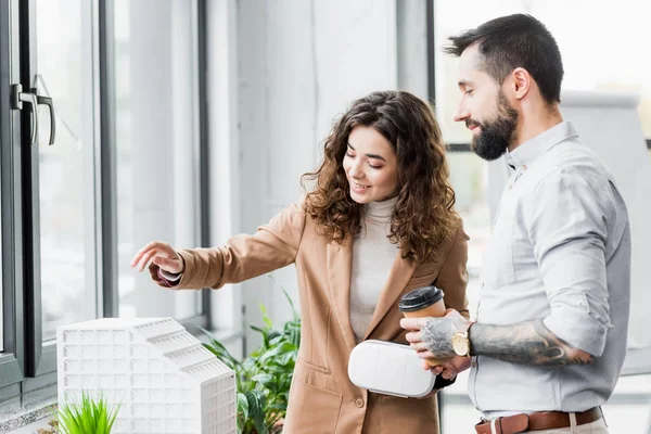 Smiling virtual reality architects looking at model of house — Stock Photo