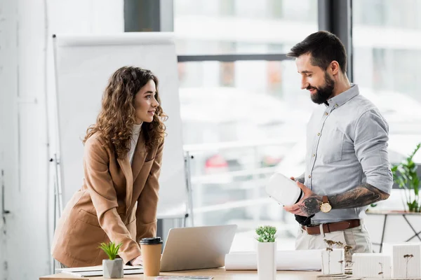 Sorridente realtà virtuale architetti in piedi vicino al modello di casa e parlando in ufficio — Stock Photo