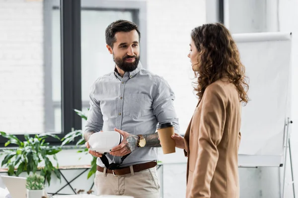 Smiling virtual reality architect holding virtual reality headset and talking with colleague — Stock Photo