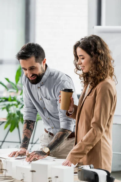 Smiling virtual reality architects looking at model of house — Stock Photo