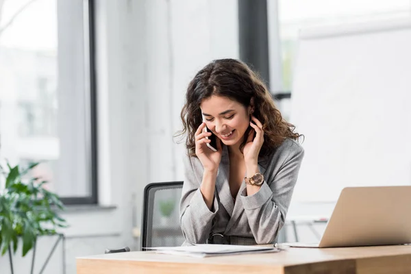 Lächelnder und attraktiver Kontoverwalter, der im Büro mit dem Smartphone spricht — Stockfoto