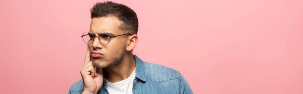 Pensive man with hand by cheek looking away isolated on pink — Stock Photo