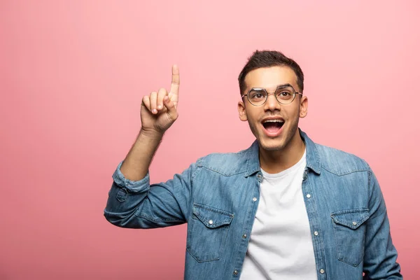 Young excited man pointing with finger and looking away isolated on pink — Stock Photo