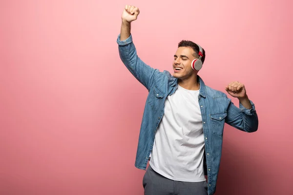 Smiling man in headphones dancing on pink background — Stock Photo