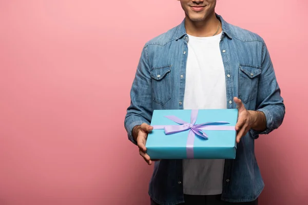 Cropped view of man holding present on pink background with copy space — Stock Photo