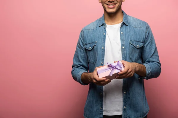 Обрізаний вид усміхненого чоловіка, що тримає подарункову коробку на рожевому фоні — стокове фото
