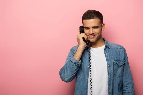 Uomo sorridente che parla sul telefono portatile su sfondo rosa — Foto stock