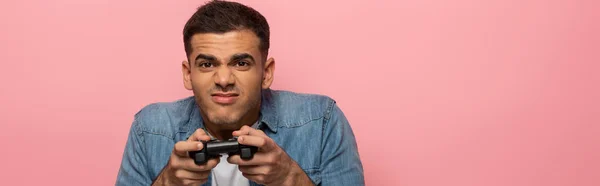 KYIV, UKRAINE - NOVEMBER 12, 2019: Panoramic shot of man grimacing while holding joystick isolated on pink — Stock Photo