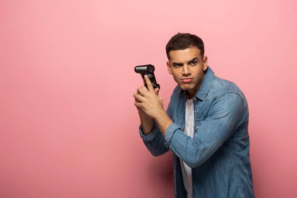 QUIIV, UCRÂNIA - NOVEMBRO 12, 2019: Bonito homem com joystick grimacing sobre fundo rosa — Fotografia de Stock