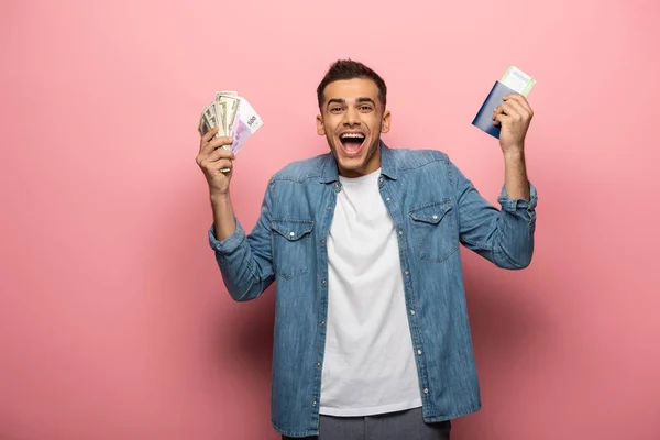 Homme excité avec argent comptant, passeport et carte d'embarquement sur fond rose — Photo de stock