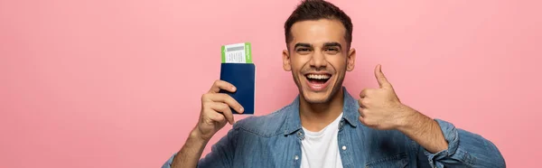 Панорамный снимок веселого человека с паспортом и посадочным талоном, показывающий, как знак изолирован на розовом — стоковое фото