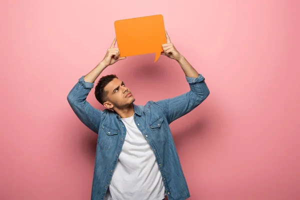 Pensive young man holding speech bubble on pink background — Stock Photo