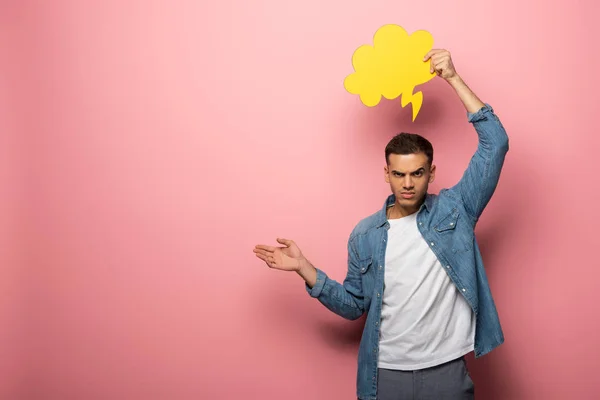 Angry man with speech bubble pointing with hand and looking at camera on pink background — Stock Photo