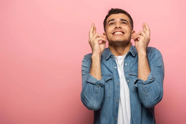 Junger Mann mit gedrückten Daumen auf rosa Hintergrund weglächeln — Stockfoto