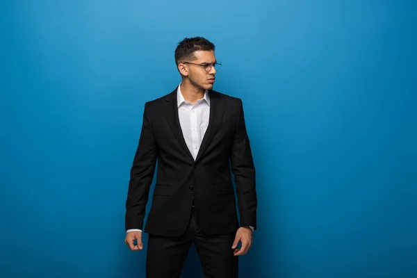 Handsome businessman looking away on blue background — Stock Photo