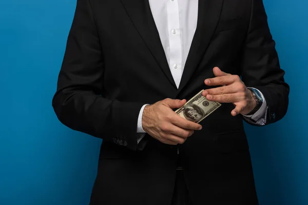 Vista cortada do empresário segurando dinheiro em fundo azul — Fotografia de Stock