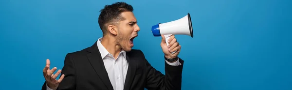 Side view of businessman screaming in loudspeaker isolated on blue, panoramic shot — Stock Photo