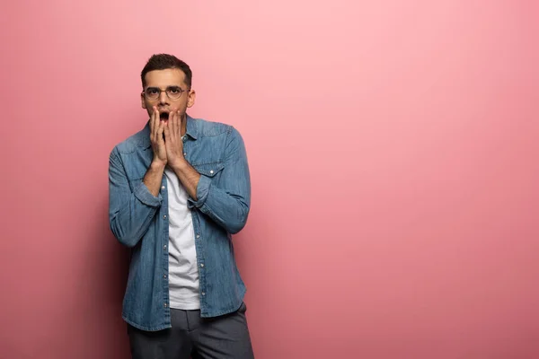 Uomo scioccato con le mani a faccia guardando la fotocamera su sfondo rosa — Foto stock