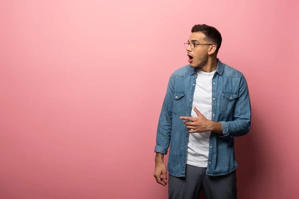 Side view of shocked man pointing with finger on pink background — Stock Photo