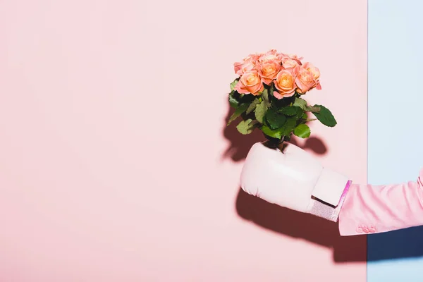 Vista ritagliata della donna in guanto da boxe tenendo bouquet su sfondo rosa e blu — Foto stock