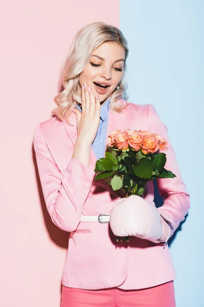 Donna scioccata in guanto da boxe tenendo bouquet su sfondo rosa e blu — Foto stock