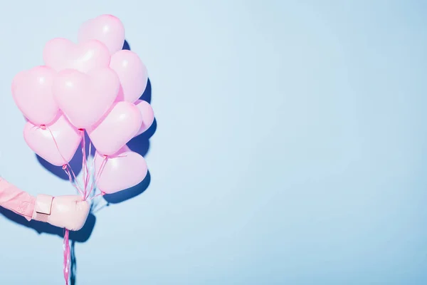 Cropped view of woman in boxing glove holding balloons on blue background — Stock Photo