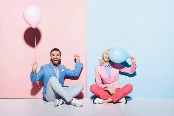 Mulher atraente e homem bonito com balões mostrando sim gesto no fundo rosa e azul — Fotografia de Stock