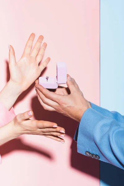 Cropped view of man doing marriage proposal to woman on pink and blue background — Stock Photo