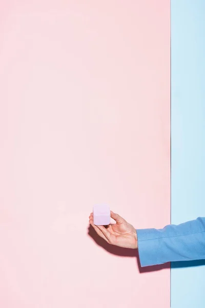 Cropped view of man holding box on blue and pink background — Stock Photo