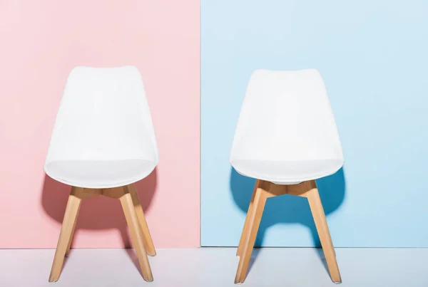 Деревянные и белые стулья на розовом и синем фоне — стоковое фото
