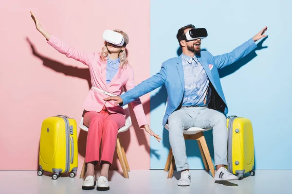Woman and smiling man in virtual reality headsets with outstretched hands on pink and blue background — Stock Photo