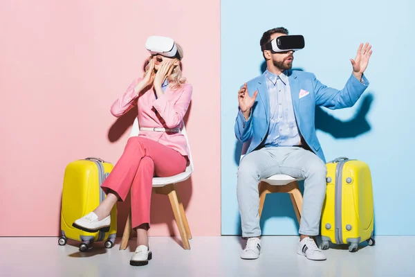 Шокированные женщина и мужчина в виртуальной реальности гарнитуры на розовом и синем фоне — стоковое фото