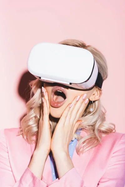 Mujer conmocionada en auriculares de realidad virtual sobre fondo rosa - foto de stock