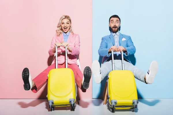 Femme choquée et bel homme tenant des sacs de voyage sur fond rose et bleu — Photo de stock