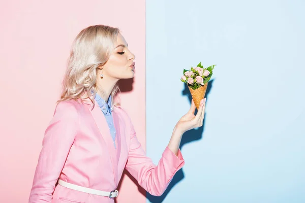 Vista laterale della donna attraente che tiene bouquet su sfondo rosa e blu — Foto stock