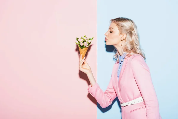 Vista laterale della donna attraente che tiene bouquet su sfondo rosa e blu — Foto stock