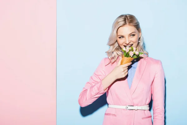Smiling woman holding bouquet on pink and blue background — Stock Photo