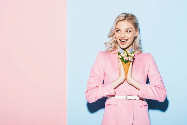 Donna sorridente che tiene bouquet su sfondo rosa e blu — Foto stock