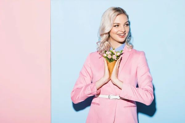 Donna sorridente che tiene bouquet su sfondo rosa e blu — Foto stock